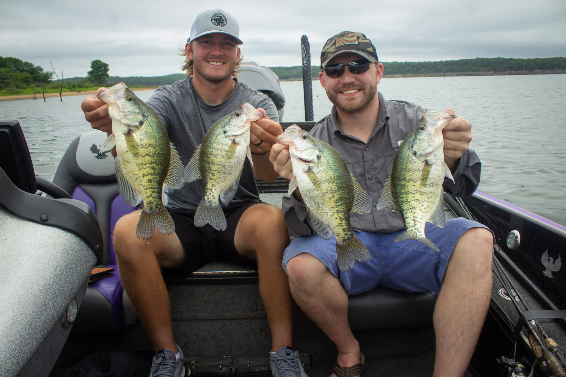 Two Missouri anglers holding a limit of crappie in a boat on a lake