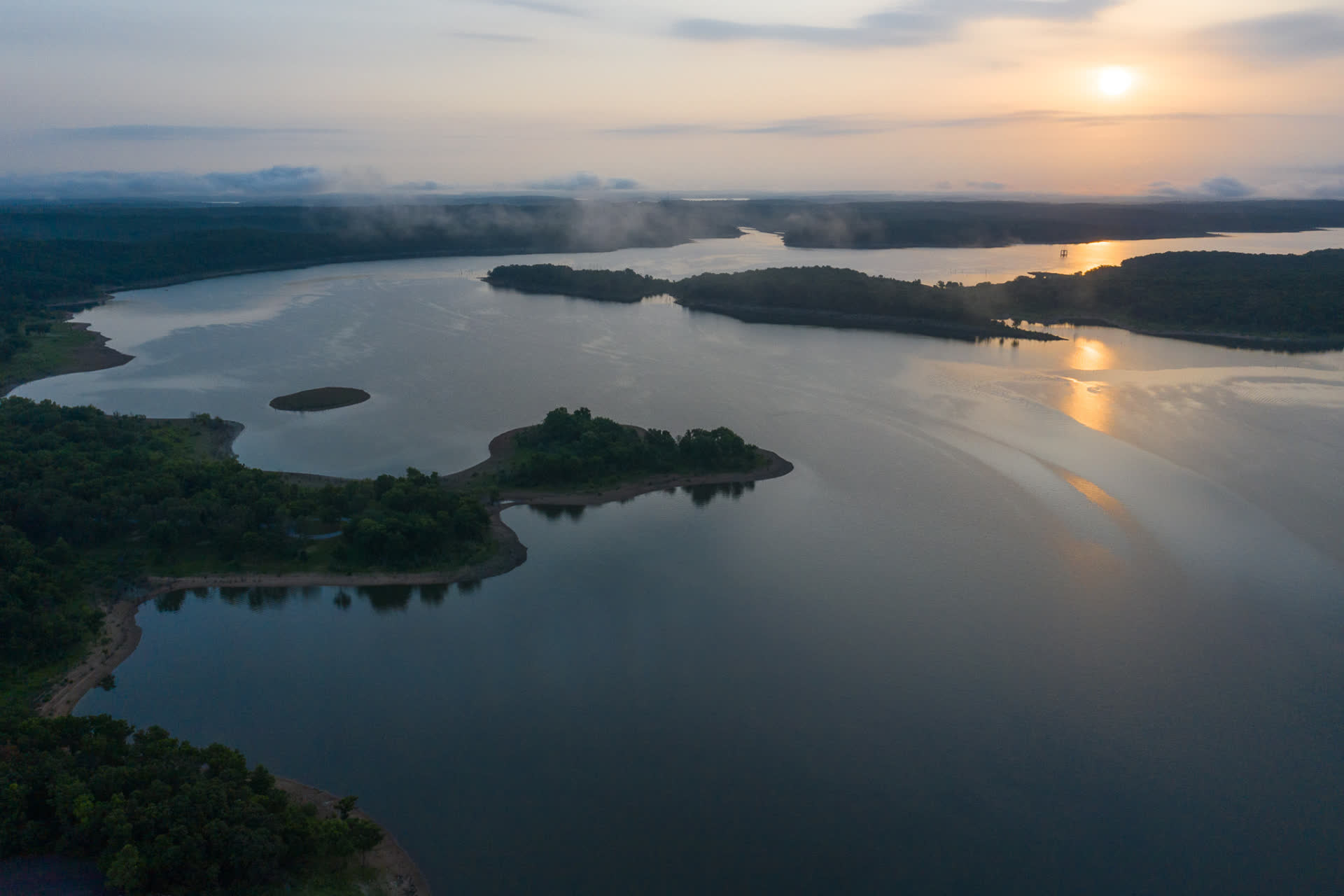 Sunrise over a Missouri lake with timbered points and calm water